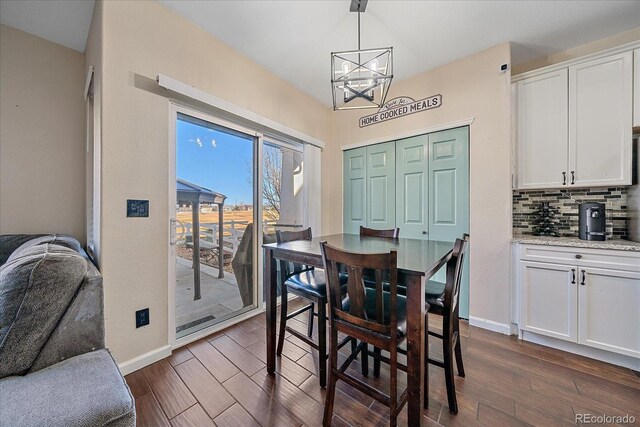 dining room featuring dark wood-type flooring, a notable chandelier, and baseboards