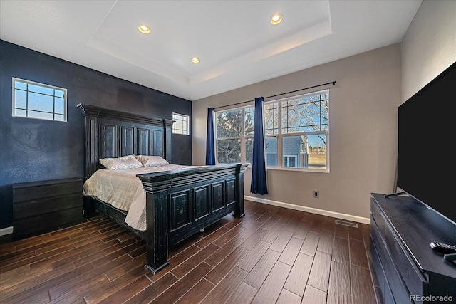 bedroom featuring a tray ceiling, multiple windows, baseboards, and wood tiled floor