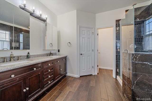 full bath with a stall shower, a sink, and wood finished floors