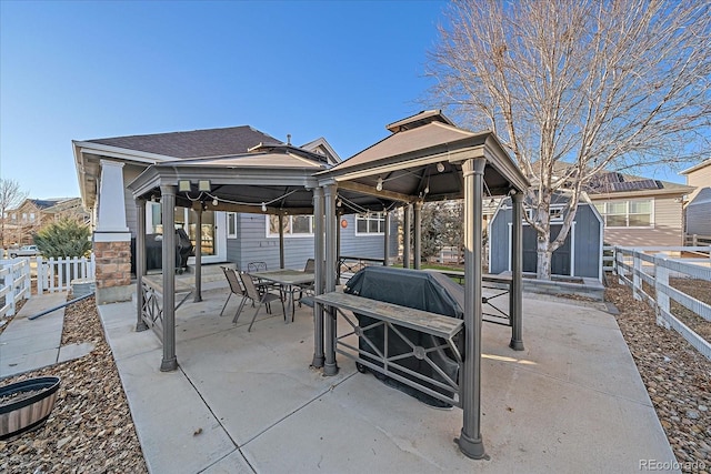 view of patio featuring an outdoor structure, a fenced backyard, outdoor dining area, and a gazebo