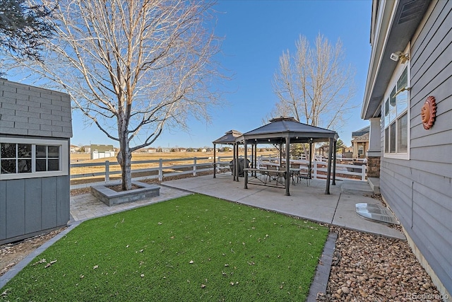 view of yard with an outbuilding, a gazebo, a patio, and fence