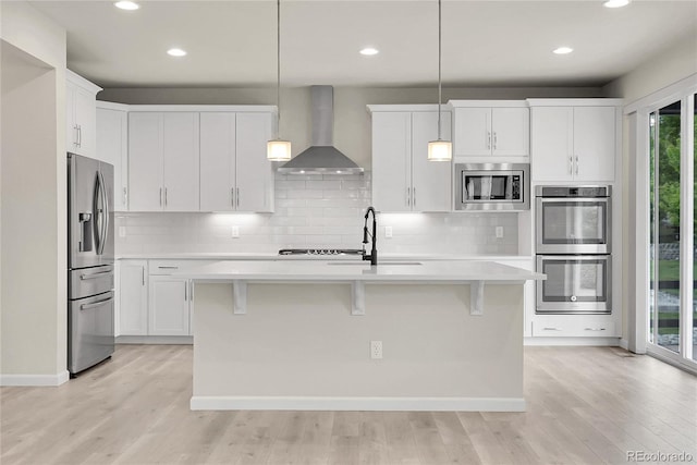 23895 E Rocky Top Pl, Aurora, CO 80016 - kitchen featuring wall chimney range hood, appliances with stainless steel finishes, light countertops, light wood-style flooring, and decorative backsplash