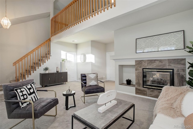 carpeted living room with a tile fireplace and a towering ceiling