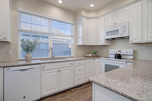 kitchen featuring white appliances, wood-type flooring, sink, and white cabinets