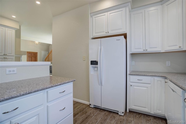 kitchen with white cabinetry, white appliances, and light stone countertops