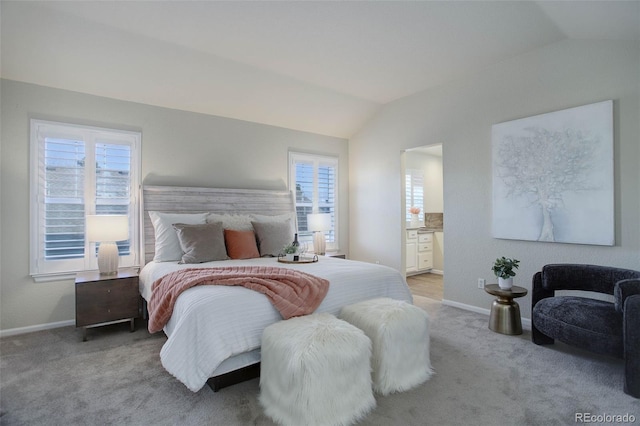 carpeted bedroom with connected bathroom and vaulted ceiling