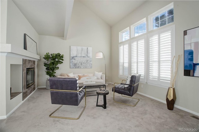 carpeted living room featuring a tile fireplace and high vaulted ceiling