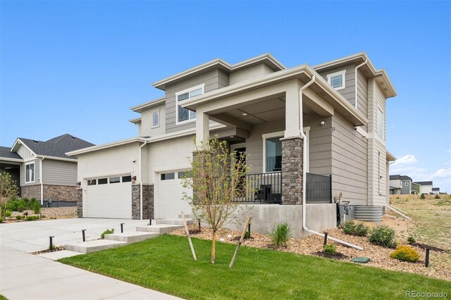 23814 E 36th Pl, Aurora, CO 80019 - prairie-style house featuring concrete driveway, a front yard, a porch, a garage, and stone siding
