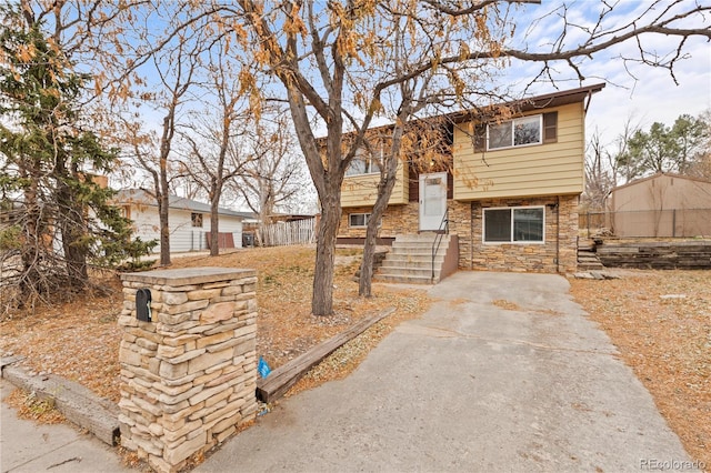 raised ranch with stone siding and fence