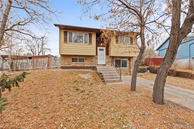 bi-level home with stone siding and fence