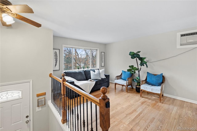 living room with light wood finished floors, an AC wall unit, and baseboards