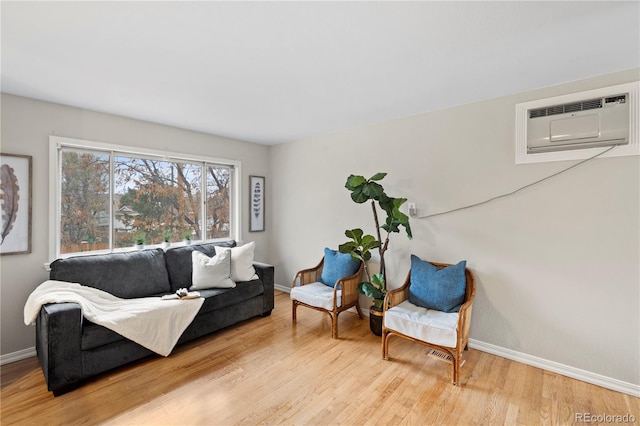 sitting room featuring wood finished floors, baseboards, and a wall mounted AC