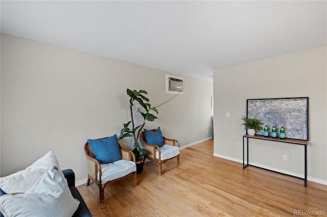 living area with light wood-style flooring, baseboards, and a wall mounted AC