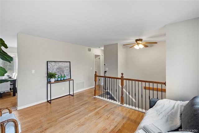 sitting room with wood finished floors, an upstairs landing, visible vents, and baseboards