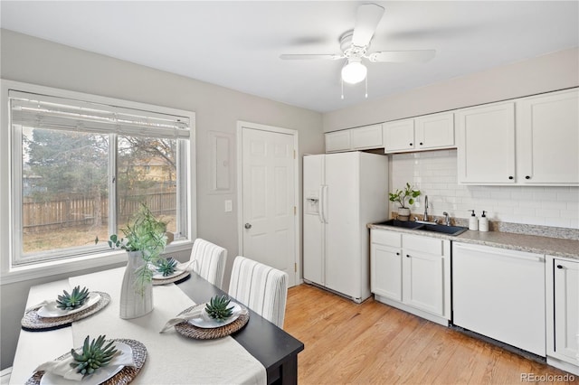 kitchen featuring tasteful backsplash, light wood-type flooring, white cabinets, white appliances, and a sink