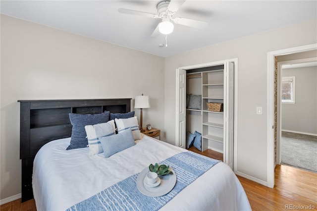 bedroom featuring a ceiling fan, wood finished floors, baseboards, and a closet