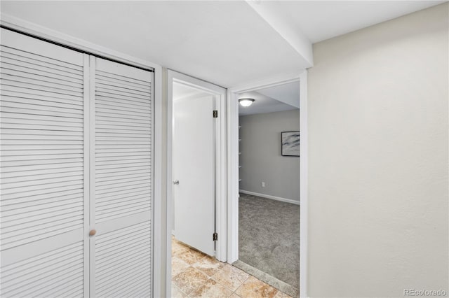 corridor featuring light colored carpet and baseboards