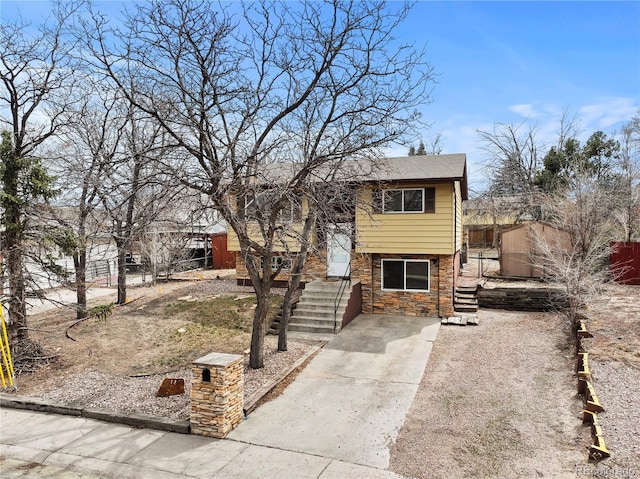 bi-level home featuring fence and stone siding