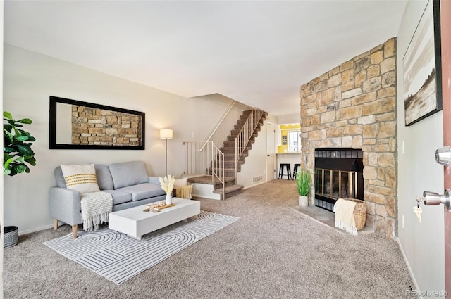 living room with carpet floors, a fireplace, visible vents, baseboards, and stairway