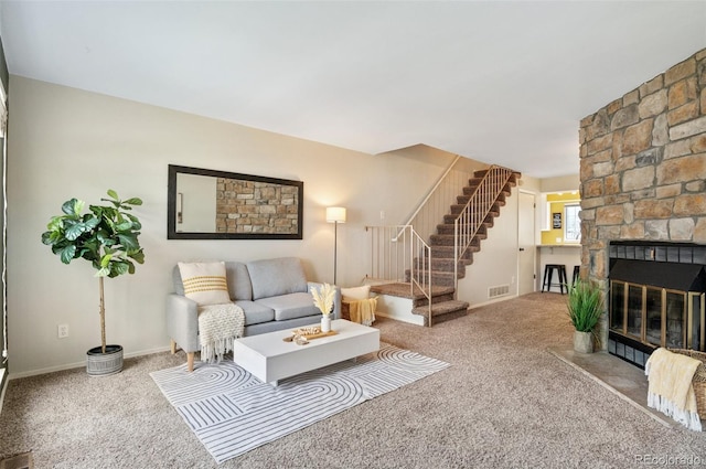 living room with baseboards, visible vents, stairway, a stone fireplace, and carpet floors