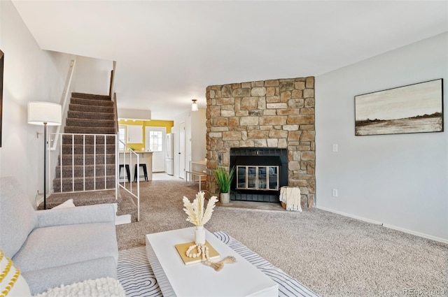 living area with carpet floors, stairway, a stone fireplace, and baseboards