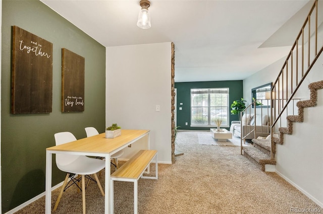 carpeted dining room with baseboards and stairway