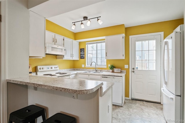 kitchen with light countertops, white cabinetry, a sink, white appliances, and a peninsula