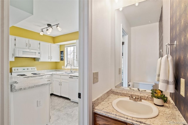 bathroom featuring toilet, rail lighting, and vanity