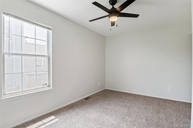 carpeted spare room with visible vents, baseboards, and ceiling fan