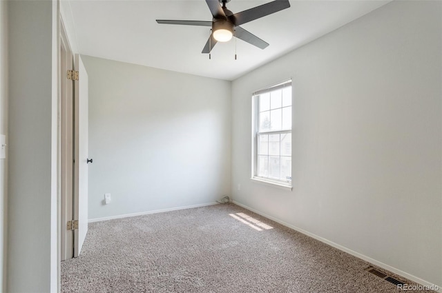 unfurnished room with carpet floors, visible vents, ceiling fan, and baseboards