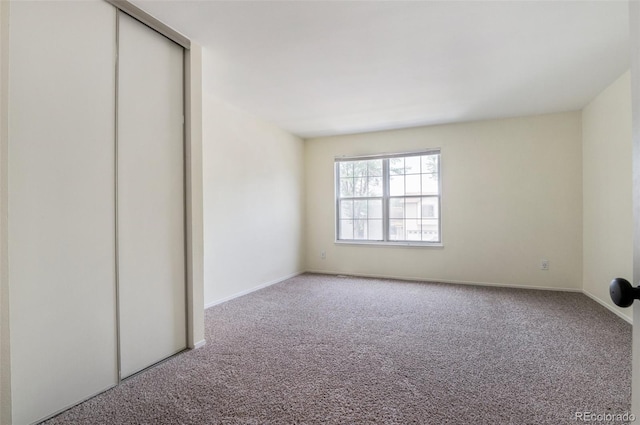 unfurnished bedroom featuring carpet floors, a closet, and baseboards