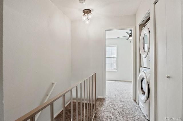 clothes washing area featuring laundry area, carpet flooring, stacked washer and clothes dryer, and baseboards