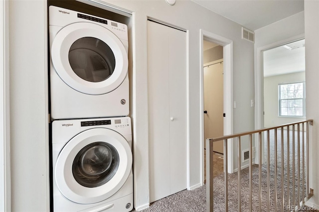 clothes washing area featuring carpet floors, stacked washer and dryer, laundry area, and visible vents