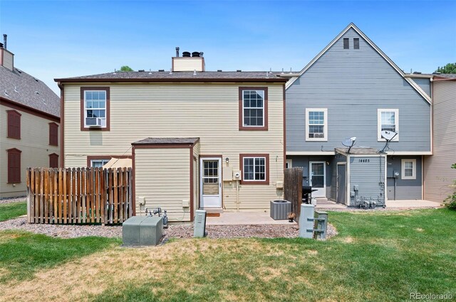 rear view of house with a patio, a chimney, central air condition unit, a lawn, and fence