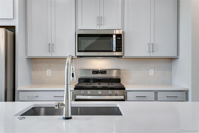 kitchen with white cabinets, appliances with stainless steel finishes, backsplash, and sink