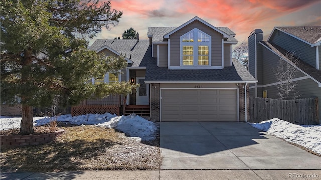 view of front of house with an attached garage, brick siding, fence, driveway, and roof with shingles