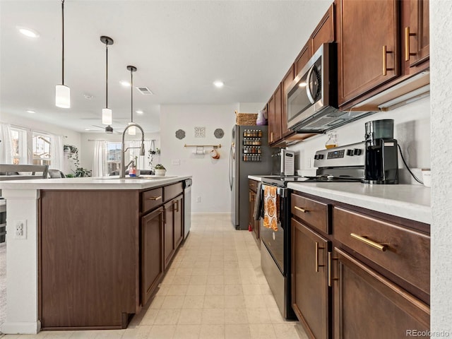 28314 E 6th Pl, Watkins, CO 80137 - kitchen featuring stainless steel appliances, a sink, a center island with sink, light countertops, and decorative light fixtures