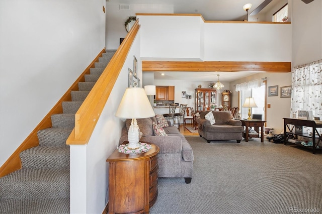 carpeted living area with beamed ceiling, a healthy amount of sunlight, a towering ceiling, and stairs