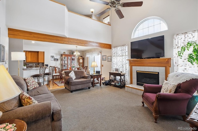 living area featuring a fireplace, carpet floors, a ceiling fan, and a towering ceiling