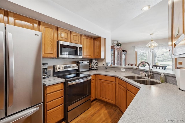 kitchen with an inviting chandelier, stainless steel appliances, light countertops, and a sink