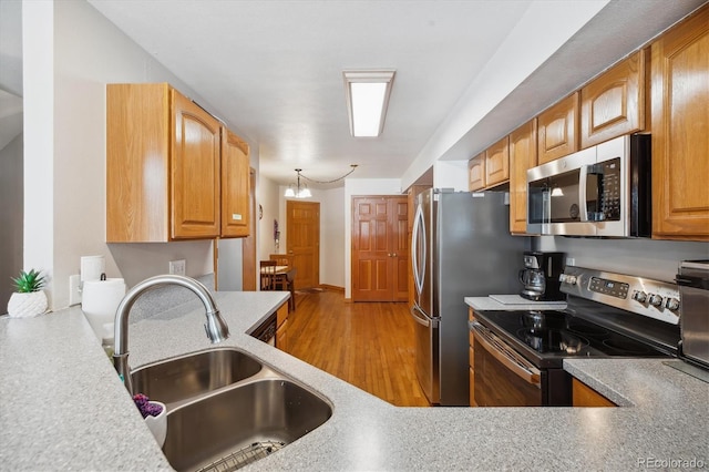 kitchen with light wood finished floors, light countertops, a sink, and appliances with stainless steel finishes