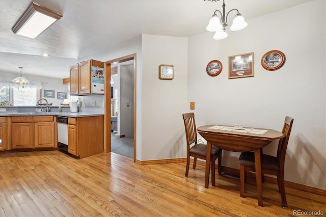 kitchen featuring a sink, white dishwasher, light wood-style floors, hanging light fixtures, and a notable chandelier
