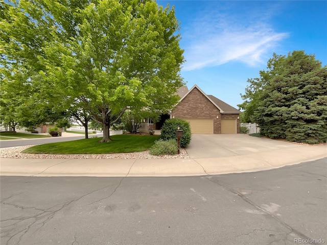 642 52nd Ave, Greeley, CO 80634 - view of property hidden behind natural elements featuring brick siding, concrete driveway, a front yard, and an attached garage