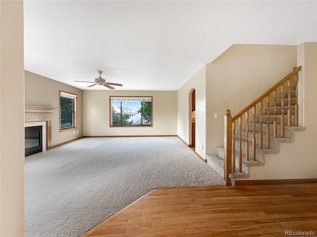 642 52nd Ave, Greeley, CO 80634 - unfurnished living room with a ceiling fan, stairs, a glass covered fireplace, wood finished floors, and carpet