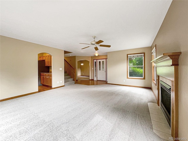 642 52nd Ave, Greeley, CO 80634 - unfurnished living room featuring arched walkways, light carpet, a fireplace, ceiling fan, and stairs