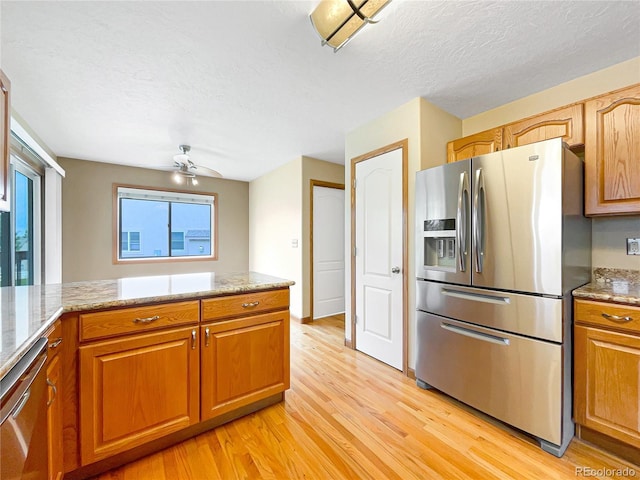 642 52nd Ave, Greeley, CO 80634 - kitchen with appliances with stainless steel finishes, light wood finished floors, ceiling fan, brown cabinets, and a textured ceiling