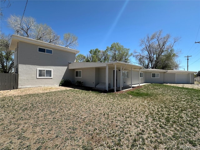 back of house featuring a yard, fence, an attached garage, and concrete block siding