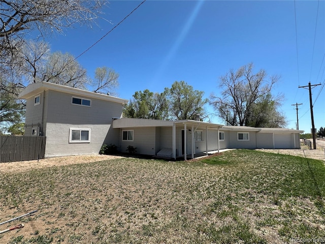 back of house featuring a yard, concrete block siding, an attached garage, and fence