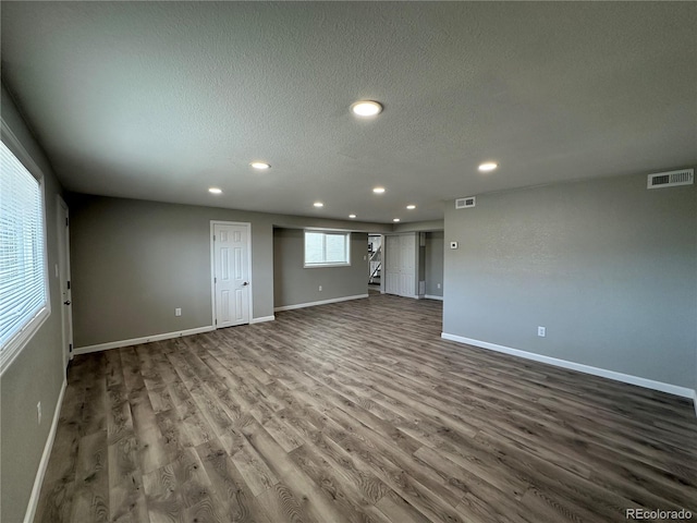 spare room featuring a textured ceiling, dark wood-type flooring, visible vents, and recessed lighting