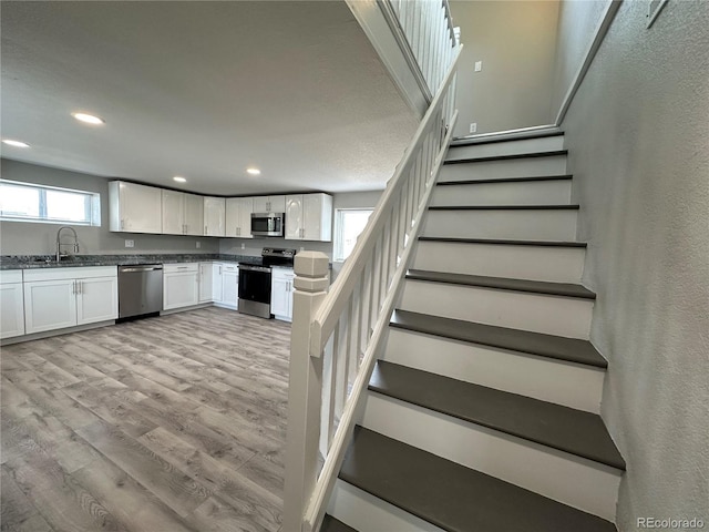 staircase with recessed lighting, a textured wall, and wood finished floors